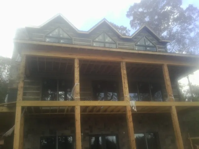 Dormers and porch framing on a large log home under construction — Roof Coating work by our crew in Burlington